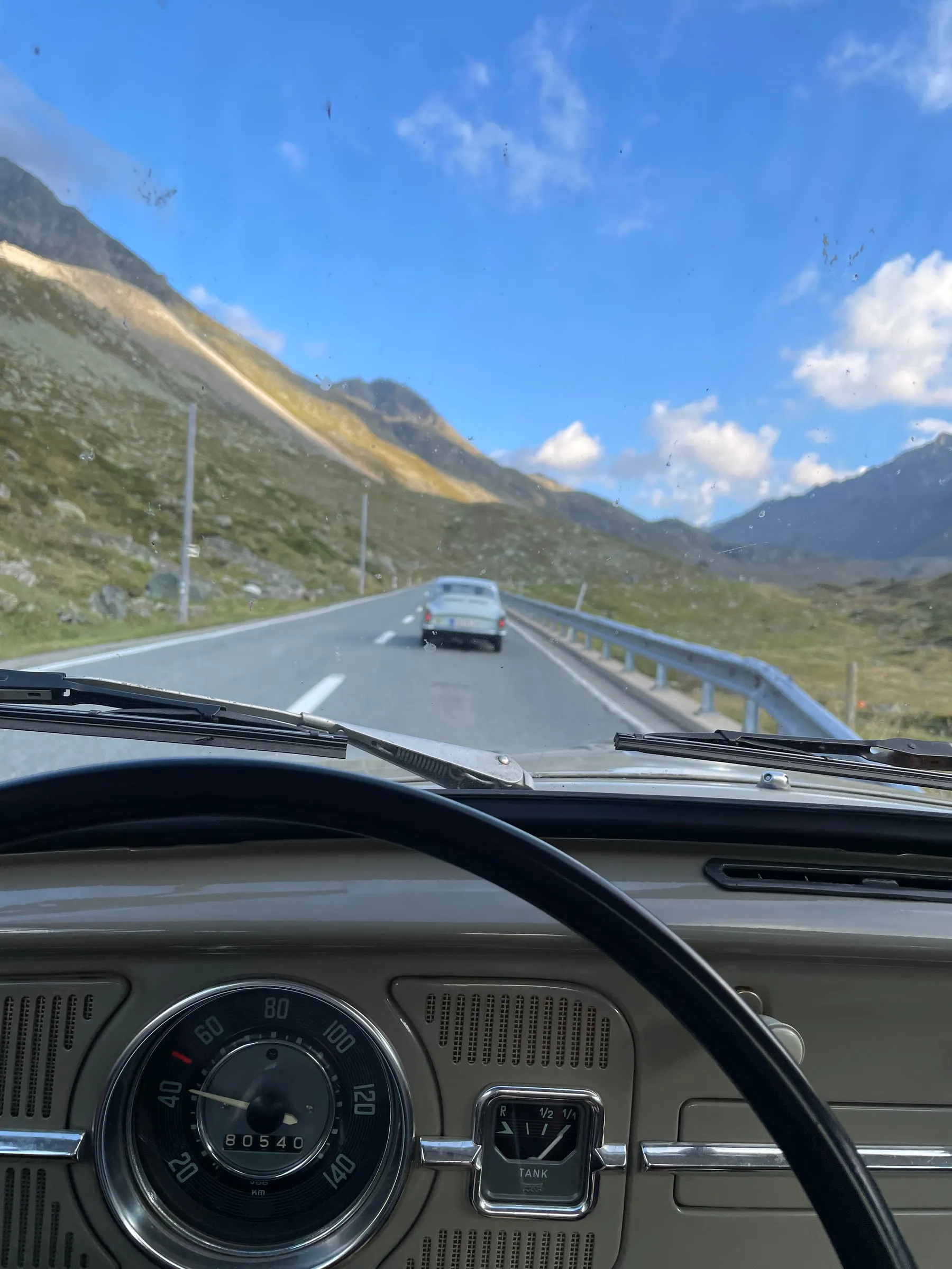 Blick durch die Frontscheibe eines Oldtimers auf eine Passstraße