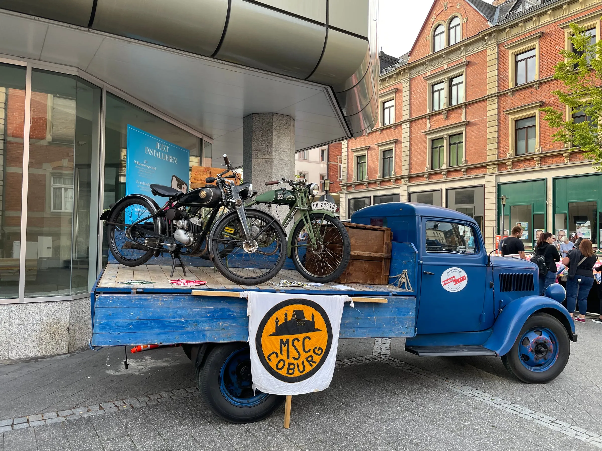 Blauer Opel Blitz mit historischen Motorrädern auf der Ladefläche und MSC-Coburg-Fahne